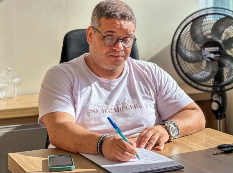 Professor Emenson Silva escrevendo à mesa