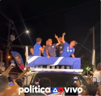 ACM Neto sobre um veículo durante carreata em Ilhéus. Trecho real de vídeo de @politicaaovivo/Instagram, com marca original preservada.