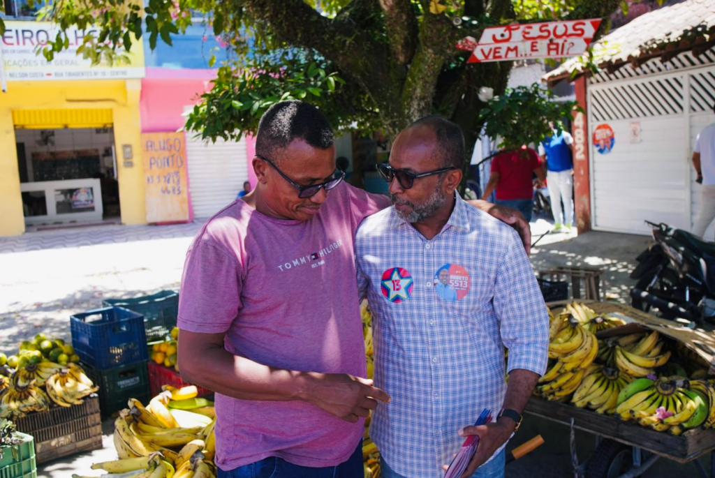 Bebeto conversa com comerciante ao lado de uma banca de frutas no bairro Nelson Costa, em Ilhéus